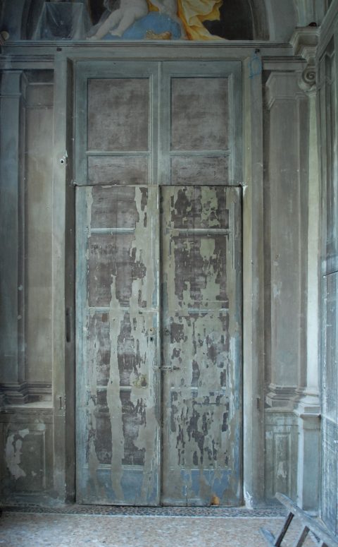 Eine Holztür – optisch versteckt in einem Trompe-l’œil – in einem historischen Innenraum